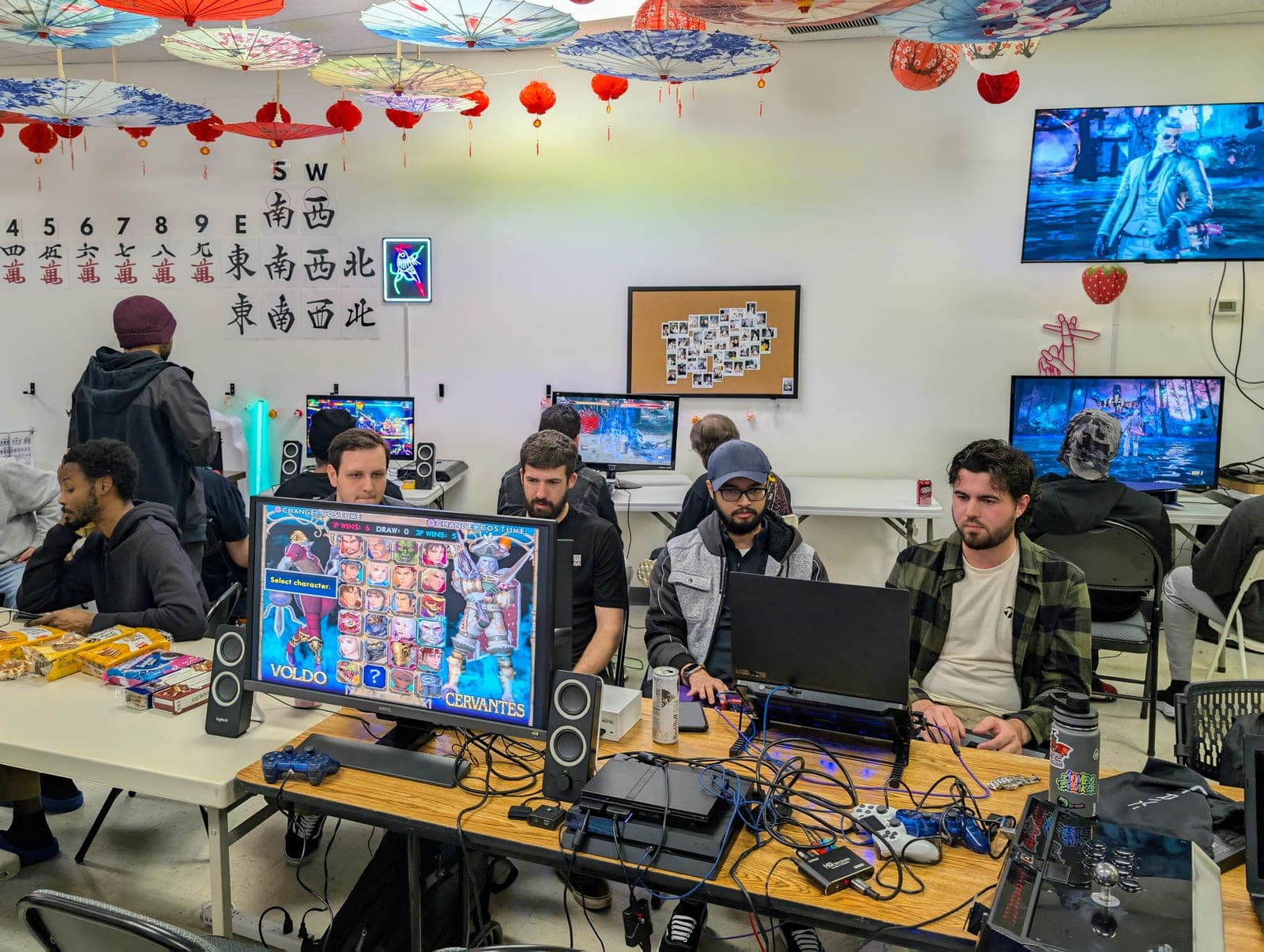 Fighting game meetup inside Setting Sun Virginia Beach with players on monitors, consoles, and arcade sticks